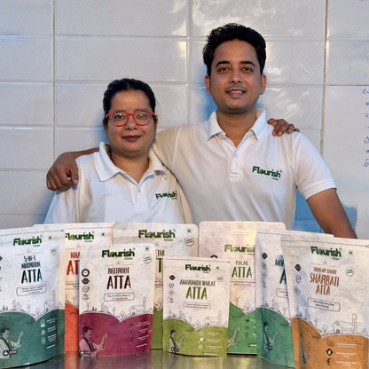 Founders Chef Sonam & Nikhil standing behind a display of Flourish atta packages against a tiled wall.